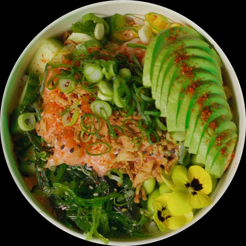 A poké bowl with salmon, seaweed, a fan of avocado, spring onion and yellow edible flowers, seen from straight above