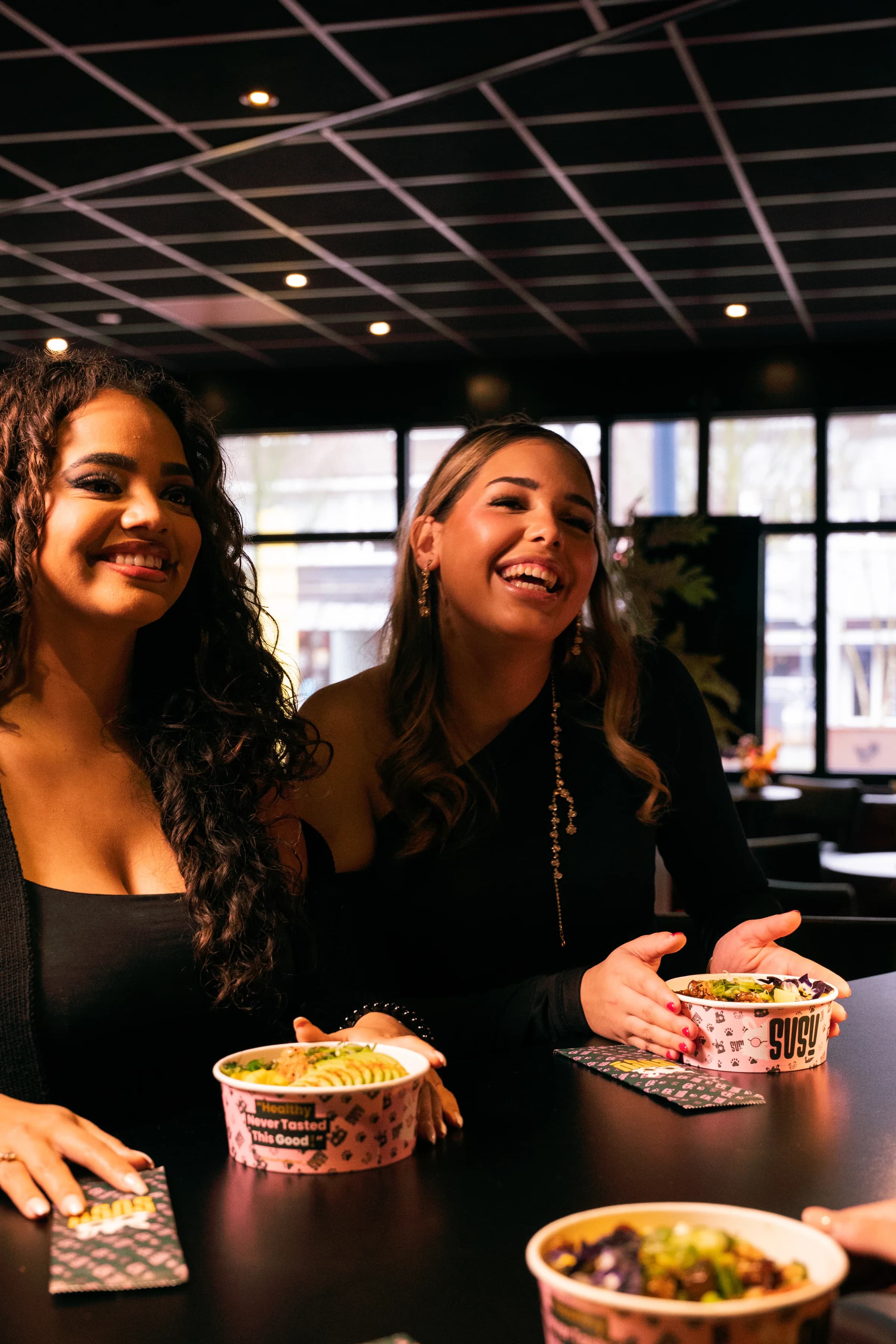 Twee lachende vrouwen aan tafel met SUSU-bowls